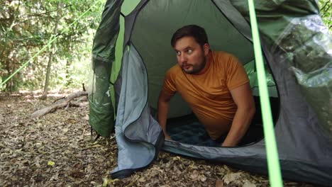Frightened-man-opens-the-zipper-of-the-tent-and-looks-around-with-a-scared-expression-on-his-face
