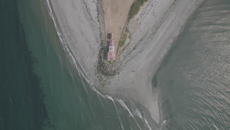 Static-aerial-footage-of-a-beach-head-with-the-West-Point-Lighthouse-at-the-tip-of-the-landmass-in-Seattle