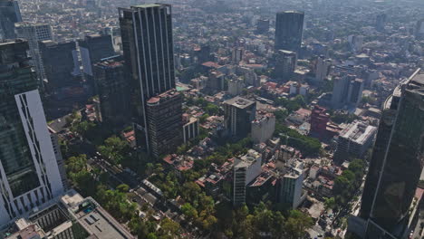 Mexico-City-Aerial-v41-flyover-and-around-paseo-de-la-reforma-capturing-downtown-cityscape,-tilt-down-reveals-traffics-at-angel-of-independence-roundabout---Shot-with-Mavic-3-Cine---December-2021