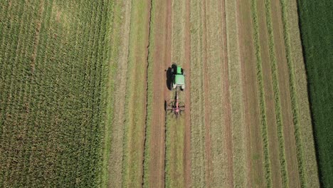 On-a-farm-field-in-southwest-Wisconsin,-a-farmer-rakes-hay-using-a-rotary-hay-rake-3
