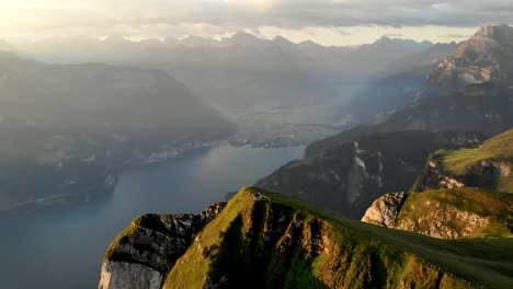 Spinning-flyover-around-the-summit-of-Niederbauen-Chulm-on-a-golden-summer-morning-in-the-Swiss-Alps-with-a-view-of-the-fjords-of-Lake-Lucerne,-Mythen,-Rigi,-Burgenstock,-Pilatus