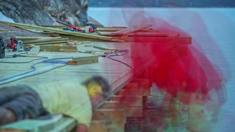 Close-up-shot-of-workers-constructing-wooden-jetty-in-timelapse-along-the-lakeside-at-daytime