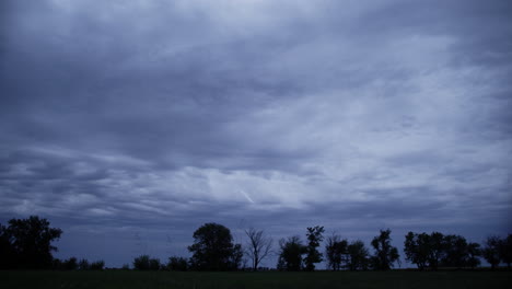 Silueta-De-árboles-Frente-Al-Cielo-Azul-Y-Nubes-De-Lluvia-Por-La-Noche-En-Tierras-De-Cultivo---Granja,-Agricultura,-Granjero,-Noche,-árboles,-Trigo,-Campo