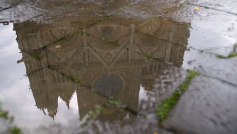 Panning-view-of-imposing-church-reflects-in-puddle