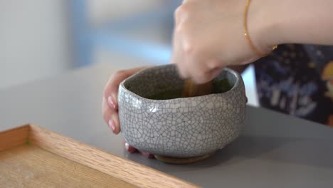 Weibliche-Hände-Mischen-Grünen-Tee-In-Der-Keramikschale-Mit-Bambusbesen,-Nahaufnahme-Handschussaufnahme-Der-Zubereitung-Traditioneller-Japanischer-Getränke,-Getränkespezialitäten