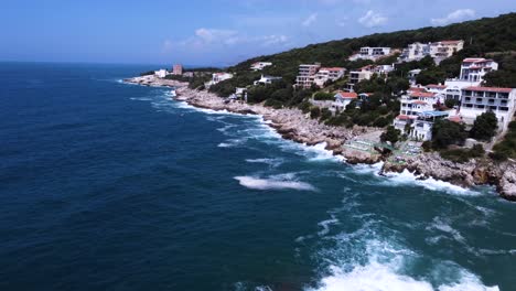 Luxury-apartment-buildings-on-rocky-shore-of-Montenegro,-waves-on-coast,-aerial