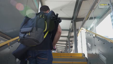 Videographer-carrying-camera-equipment-up-flight-of-stairs
