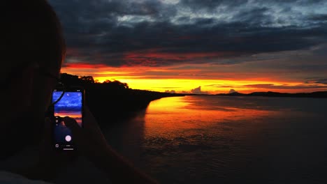 Junger-Mann,-Der-Mit-Seiner-Instagram-app-Auf-Seinem-Telefon-Den-Sonnenuntergang-In-Costa-Rica-Fotografiert