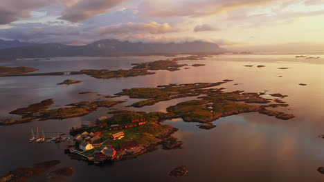Aerial-view-around-a-island-village-towards-the-Atlantic-ocean-road,-sunset-in-Norway---circling,-drone-shot