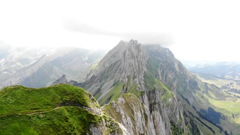 Aerial-flyover-over-the-cliffs-of-Schafler-ridge-in-Appenzell,-Switzerland-towards-Altenturm-peak-on-a-cloudy-summer-day-with-a-view-of-one-of-Switzerland's-most-popular,-yet-dangerous-hiking-trails-1