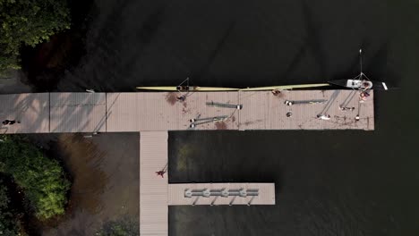 Steady-aerial-top-down-view-of-a-rowing-landing-stage-and-training-facility-in-the-city-lake-of-Rio-de-Janeiro-with-rowers-arriving-and-coming-out-of-the-water-taking-the-boats-to-storage-out-of-frame