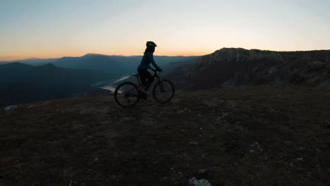 Mädchen-Mit-Dem-Fahrrad-Bergauf-Auf-Einem-Berg-Bei-Sonnenuntergang