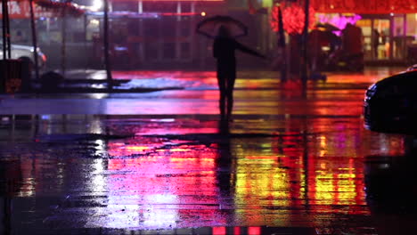 Cinemagrafía-De-Una-Mujer-Por-La-Noche-En-Una-Carretera-Que-Se-Queda-Quieta-Con-Un-Paraguas-Mientras-Llueve