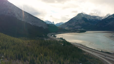 Drone-aerial-view-of-mountains,-highway-and-lake-at-golden-hour