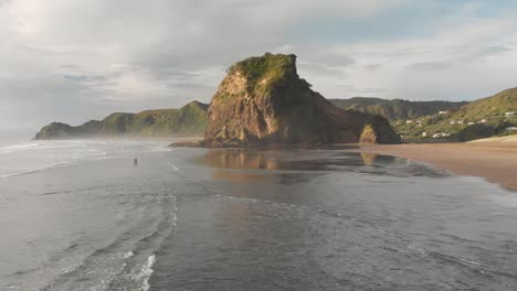 SLOWMO---Incredible-aerial-drone-shot-over-black-sand-Piha-Beach-in-New-Zealand-during-sunset