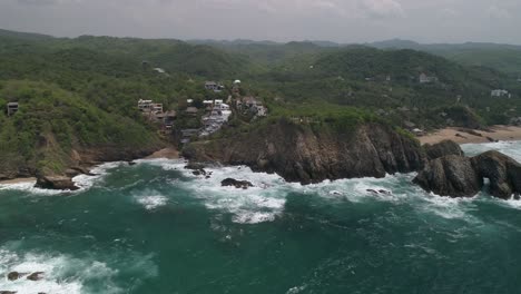 Aerial-drone-shot-of-Zipolite-coastline-with-some-hotels-and-houses