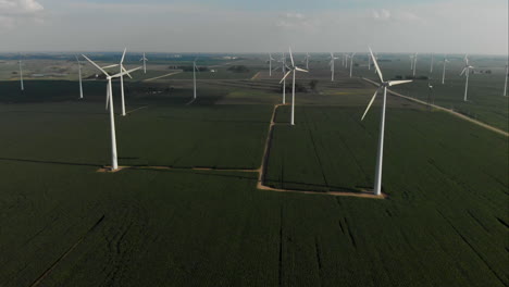 Volando-Alto-Sobre-Un-Campo-Verde-De-Soja-Hacia-Una-Granja-De-Turbinas-Eólicas-En-Iowa
