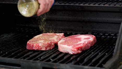 Gewürze-Zwei-Rib-Eye-Steaks-In-Zeitlupe-Aufsetzen