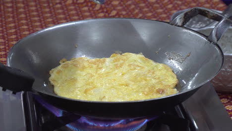 Close-up-view-of-a-an-omelet-being-cooked-on-a-steel-wok-on-a-butane-stove