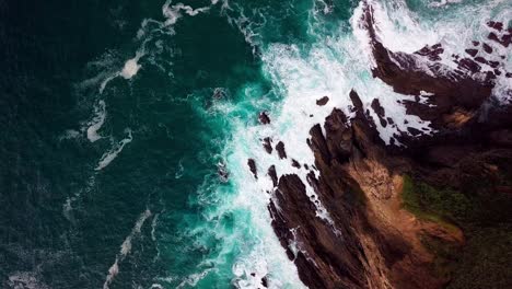 Ocean-Waves-Break-on-Rock-Cliff-in-Big-Sur-Cali,-Wide-Overhead-Drone-Shot