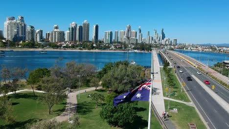 Australische-Flagge-Weht-Im-Wind-In-Der-Nähe-Eines-Parks-Und-Einer-Straße