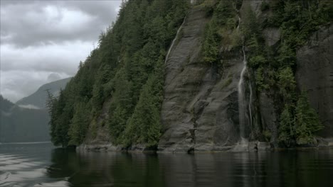 Una-Montaña-Rocosa,-En-Un-Fiordo-De-Alaska,-Presenta-Varias-Cascadas-Pequeñas-Mientras-La-Cámara-Gira-Alrededor-De-La-Montaña-Misma