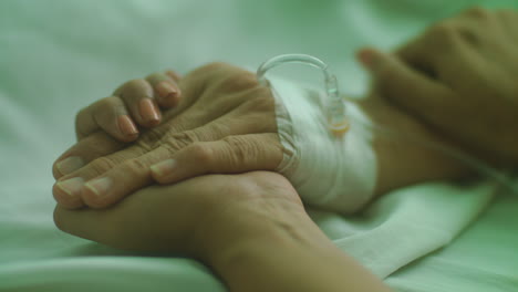 Close-Up-of-Old-and-Sick-Patient-Holding-Hands-With-A-Woman