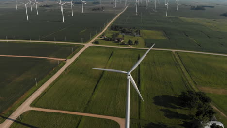 Flying-high-above-and-panning-down-on-a-wind-turbine-in-a-field-of-green-crops-and-farmland