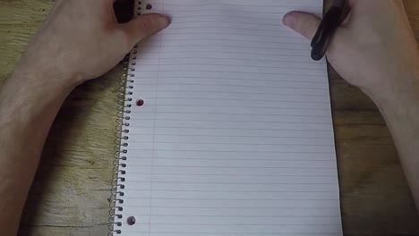 Person-looking-down-at-a-paper-note-book-with-a-pen-in-hand-not-knowing-what-to-write
