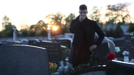 Sad-man-standing-in-front-of-a-grave-during-sunset,-4k-footage