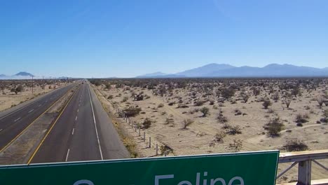 View-of-a-drone-flying-towards-over-a-sign-on-a-highway-that-says-"Bienvenidos-a-San-Felipe