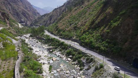 Drone-Shot-of-a-small-road-and-river-in-Himachal-Pradesh-near-Manali,-Kasol-3
