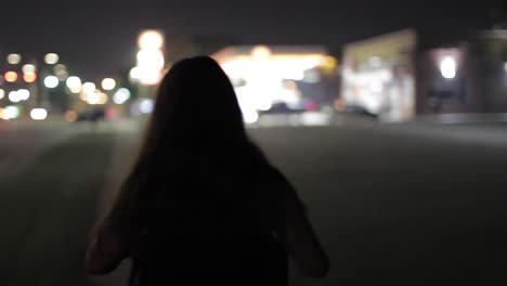Tracking-Shot-From-Behind-A-Young-Woman-With-A-Blurry-Gas-Station-In-The-Background