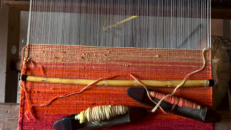 Weaving-Braiding-Manual-Machine-and-Tools-in-Traditional-Rugs-Workshop-Handicraft-Manufacture,-Oaxaca-Mexico,-Manual-Creative-Artisan-Fabric-Handloom-Craftwork,-Beautiful-Red-Colored-Rug-in-Progress