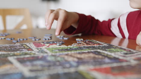 Close-up-of-child-hands-assemble-puzzle-together-having-fun,-enjoy-game-at-home-sitting-on-the-table-in-the-livingr-room