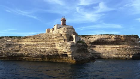 Erstaunlicher-Blick-Aus-Niedrigem-Winkel-Auf-Den-Berühmten-Madonnetta-Leuchtturm,-Der-Auf-Einer-Klippe-Im-Süden-Der-Insel-Korsika-Thront,-Vom-Ausflugsboot-Aus-Gesehen