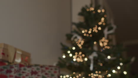 Christmas-presents-under-the-Christmas-tree-with-lights,-Tilt,-Handheld,-Mediumwide