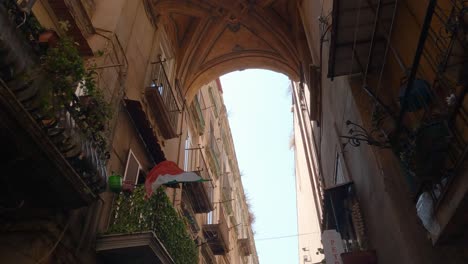 Italian-flag-waving-on-a-balcony,-streets-of-Naples,-Italy