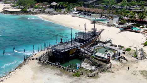 Beautiful-ancient-wooden-ship-moored-near-luxury-resorts-of-Bali,-aerial-orbit-view