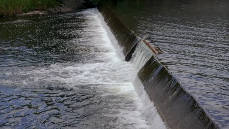 Water-gently-flows-over-a-concrete-dam-in-a-small-stream