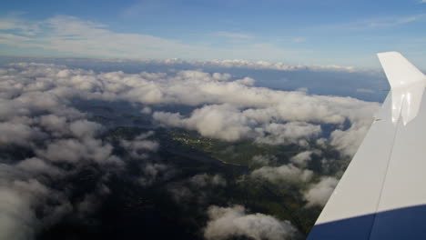 Toma-Aérea-Desde-Un-Avión-Mirando-A-Través-De-Las-Nubes-Hacia-Las-Montañas-De-Abajo
