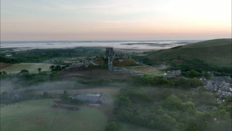 Aerial-view-of-Corfe-Castle-on-a-misty-morning,-Dorset-,-England,-UK