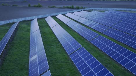 Aerial-pullback-reveals-rows-of-solar-panels-on-commercial-solar-farm---green-energy-production-harnessing-sun-energy,-Racari,-Romania