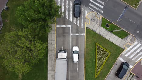 Drone-4k-top-down-video,-looking-down-on-cars-in-a-street-starting-to-drive-forward-to-a-street-crossing-and-drone-follows