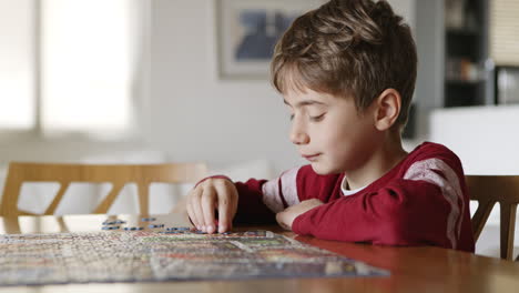 Side-view-of-a-boy-assemble-puzzle-together-having-fun,-enjoy-game-at-home-sitting-on-the-table-in-the-livingr-room