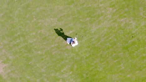 Newlywed-couple-slowly-dancing-alone-on-green-lawn,-overhead-view