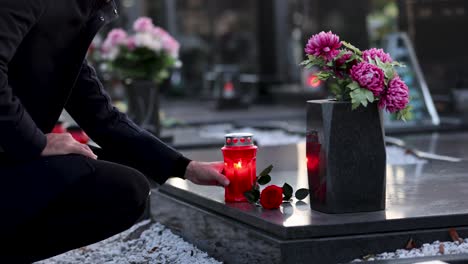 Man-placing-a-candle-on-the-grave