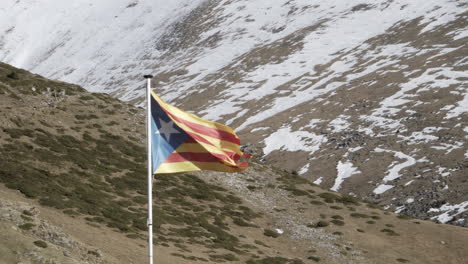4k-clip-Einer-Nahaufnahme-Der-Sternenklaren-Estelada-unabhängigkeitsflagge-Von-Katalonien,-Die-Im-Wind-In-Den-Feldern-Auf-Einem-Schneebedeckten-Berg-Im-Winter-In-Spanien-Weht