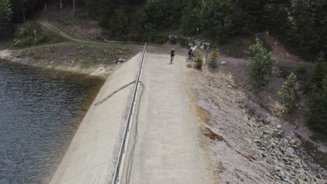 Three-mountain-biker-starting-on-the-dam-wall-of-lac-d'altenweiher-in-the-french-vosges