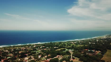 Luftaufnahmen,-Die-Von-Einer-Drohne-Von-Scottburgh-Beach-Und-Landgrasfeldern-Mit-Wohnhäusern-Mit-Blick-Auf-Das-Meer-In-Kwa-Zulu,-Natal,-Südafrika,-Gefilmt-Wurden